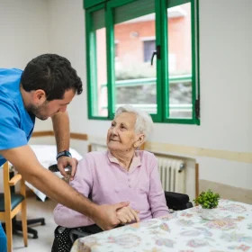 cuidadora-ayudando-a-una-mujer-mayor-en-una-residencia