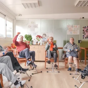 cuidadores-amables-supervisando-a-personas-mayores-mientras-hacen-ejercicio